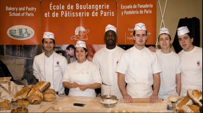 Sébastien (centre) with fellow trainees at a bakery and pastry school in Paris, fresh loaves on the counter